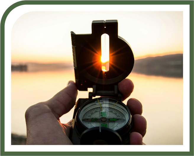 A person holding an open compass in front of the sun.